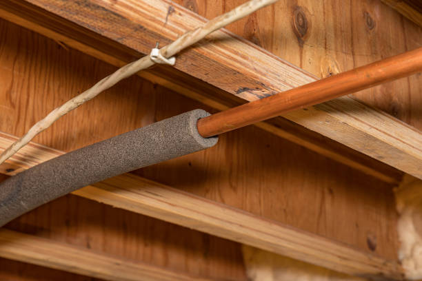 Copper water pipe partially wrapped in foam insulation attached to wooden joists.