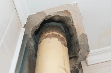 Old corroded drain pipe exposed inside a wall cutaway for San Diego sewer line repair guide.