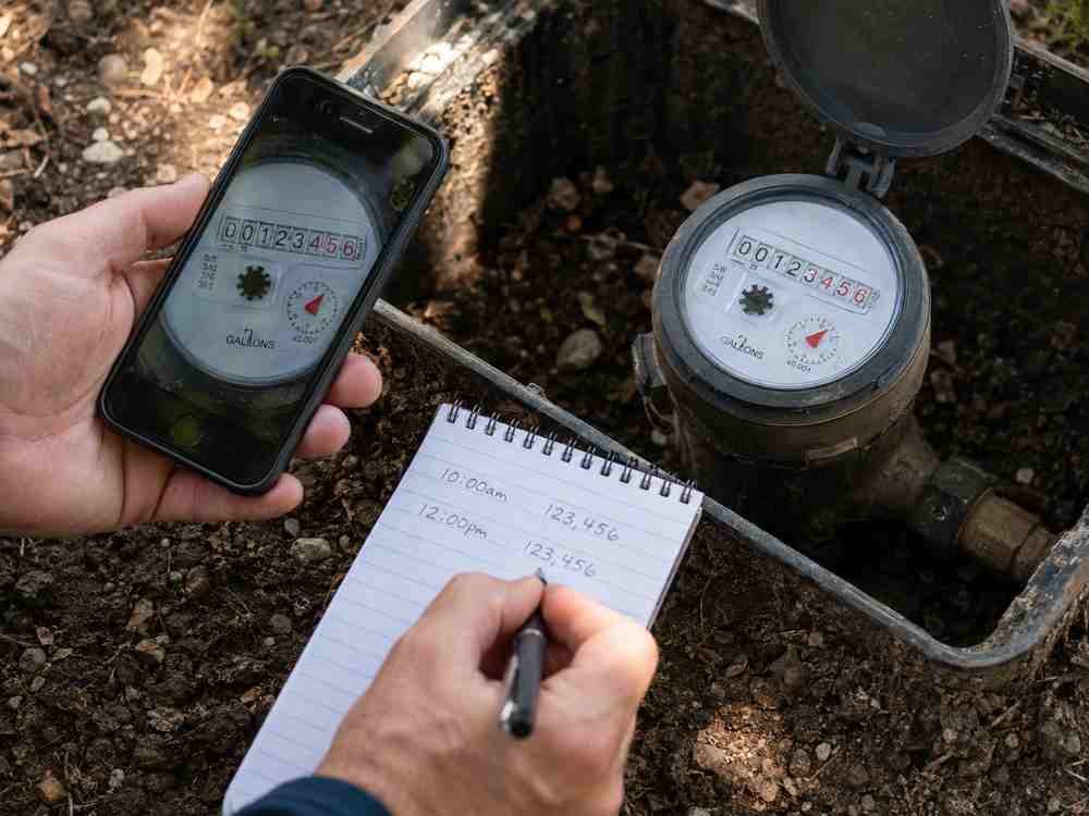 Homeowner comparing and recording water meter readings to check for a hidden plumbing leak in San Diego.