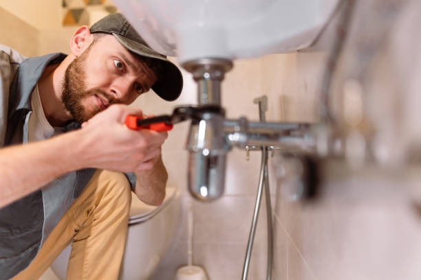 Licensed San Diego plumber tightening chrome p-trap plumbing under bathroom sink.