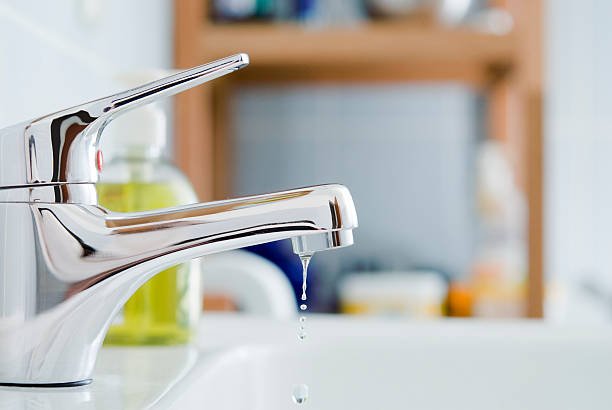 A dripping chrome bathroom faucet, demonstrating how hard water scale eventually damages internal cartridges and rubber seals.